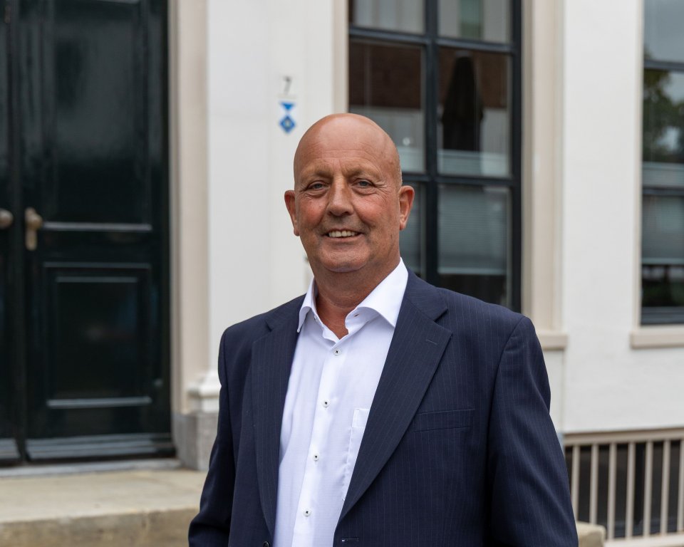 Wethouder Alex Walter staand voor gemeentehuis.