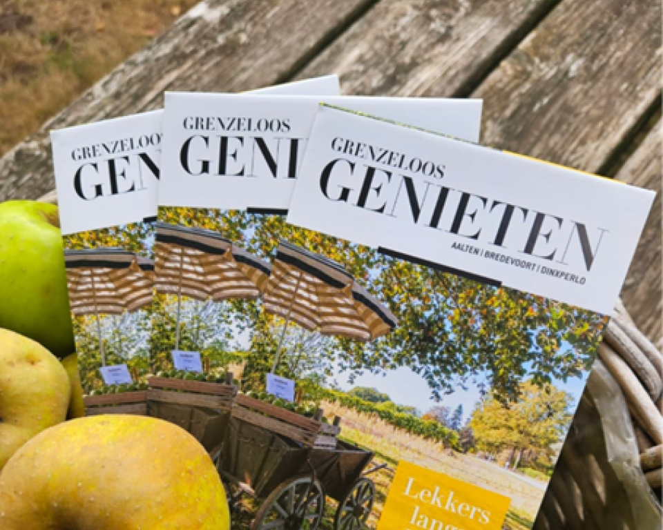 Mand met appels waar de folder Grenzeloos Genieten in ligt.