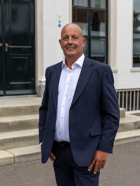 Wethouder Alex Walter staand voor gemeentehuis.