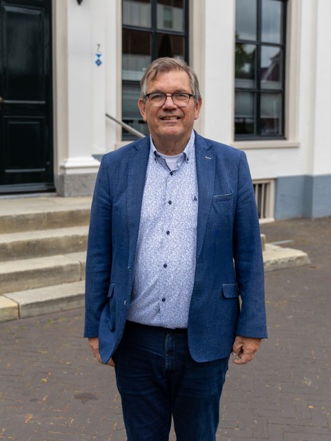 Wethouder Joop Wikkerink staand voor gemeentehuis.