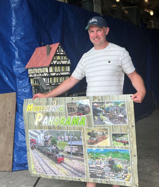 Man in een hal met een poster van modelspoor Panorama