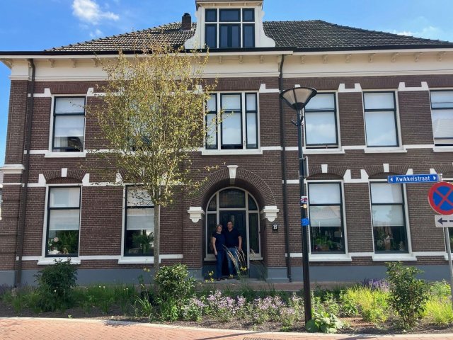 Man en vrouw voor groot karakteristiek huis met veel ramen