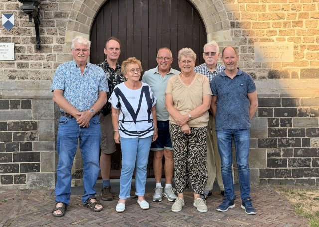 5 mannen en 2 vrouwen staand voor de houten deur van een kerk