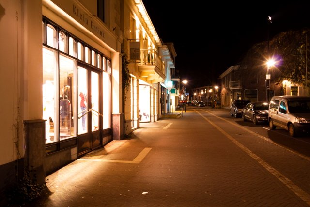 Landstraat in Aalten, verlichte etalage waardoor de openbare verlichting wegvalt en het donker op straat lijkt. 