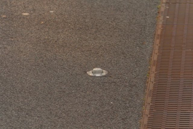 Wegdek met een kattenoog, glazenbol die licht reflecteert.