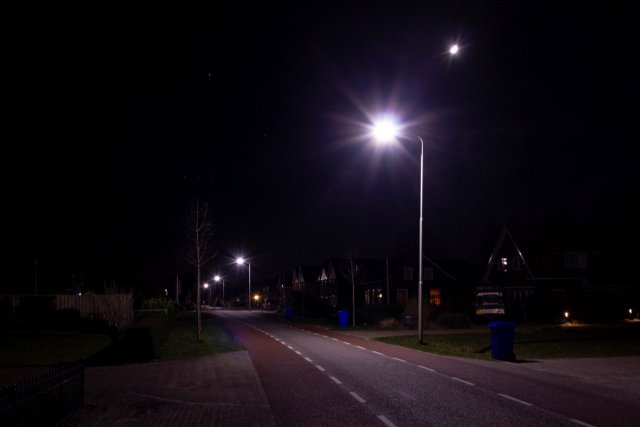Foto van brandende lantaarnpaal waarbij het licht mooi verdeeld is over de weg.