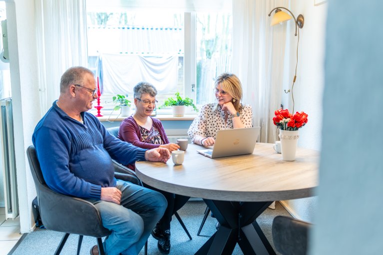 Bewoners zitten aan de keukentafel met een laptop