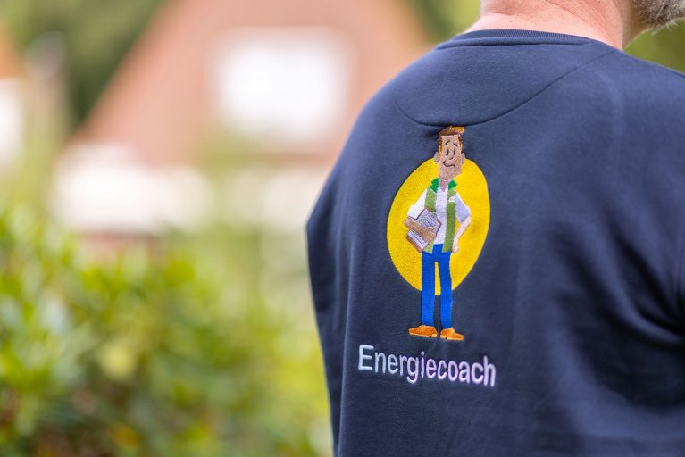 Rug van energiecoach met op zijn blauwe trui het logo van energiecoach geborduurd