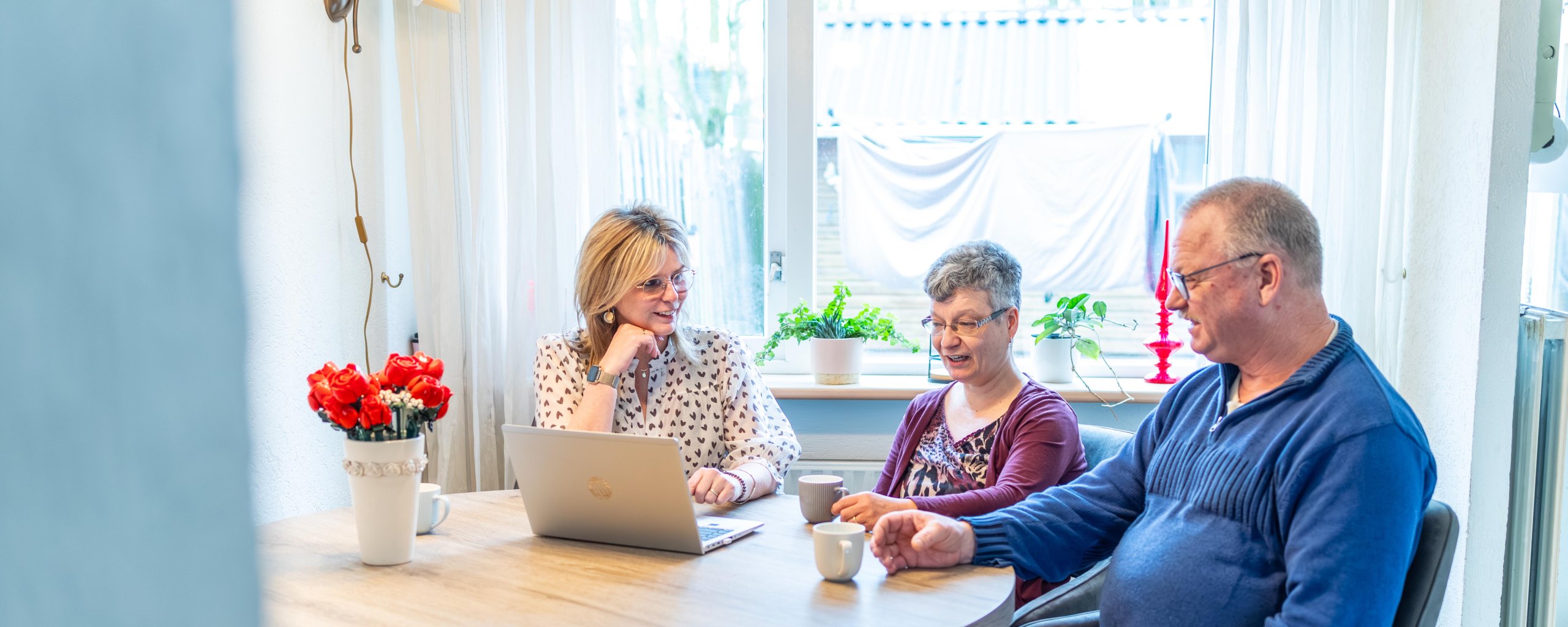 Bewoners zitten aan de keukentafel met een laptop