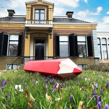 Jeltingahuis met op het gras een groot rood potlood