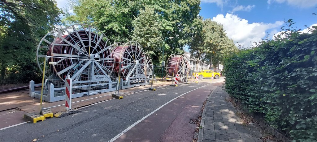 Opgerolde kabels op ca. 3 meterhoge haspels langs de weg