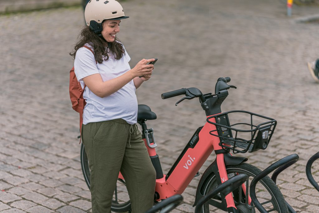 Vrouw bij een deelfiets van Voi