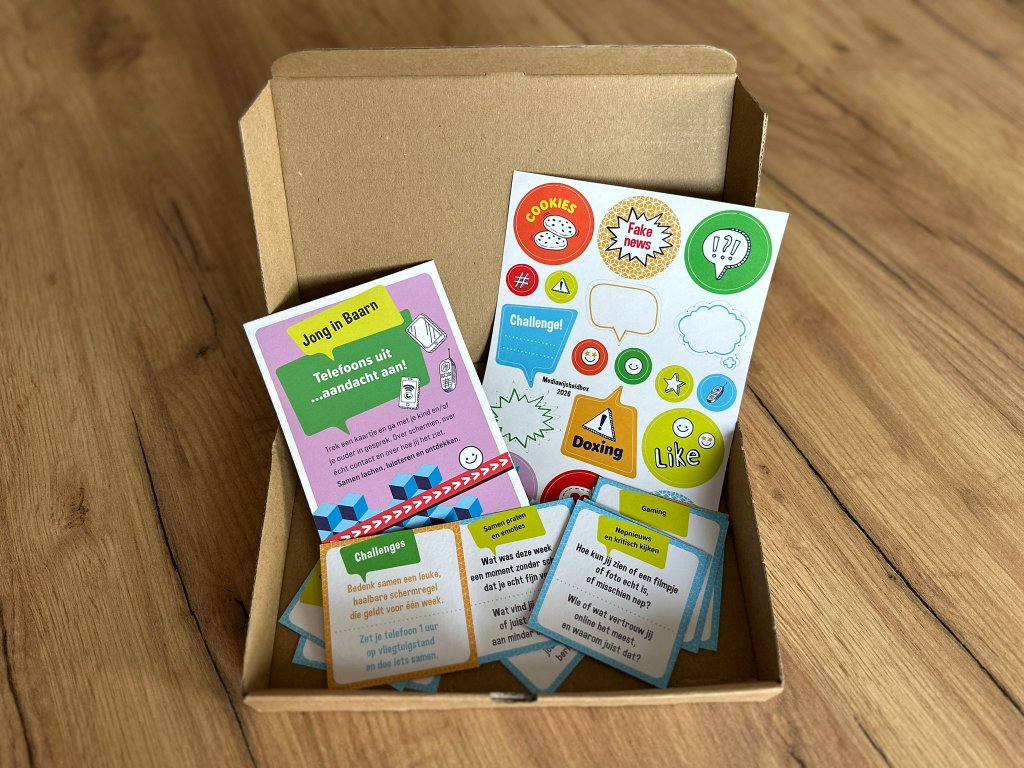 Een doosje gevuld met flyer, kaarten, stickers en andere communicatiematerialen in vrolijke kleuren