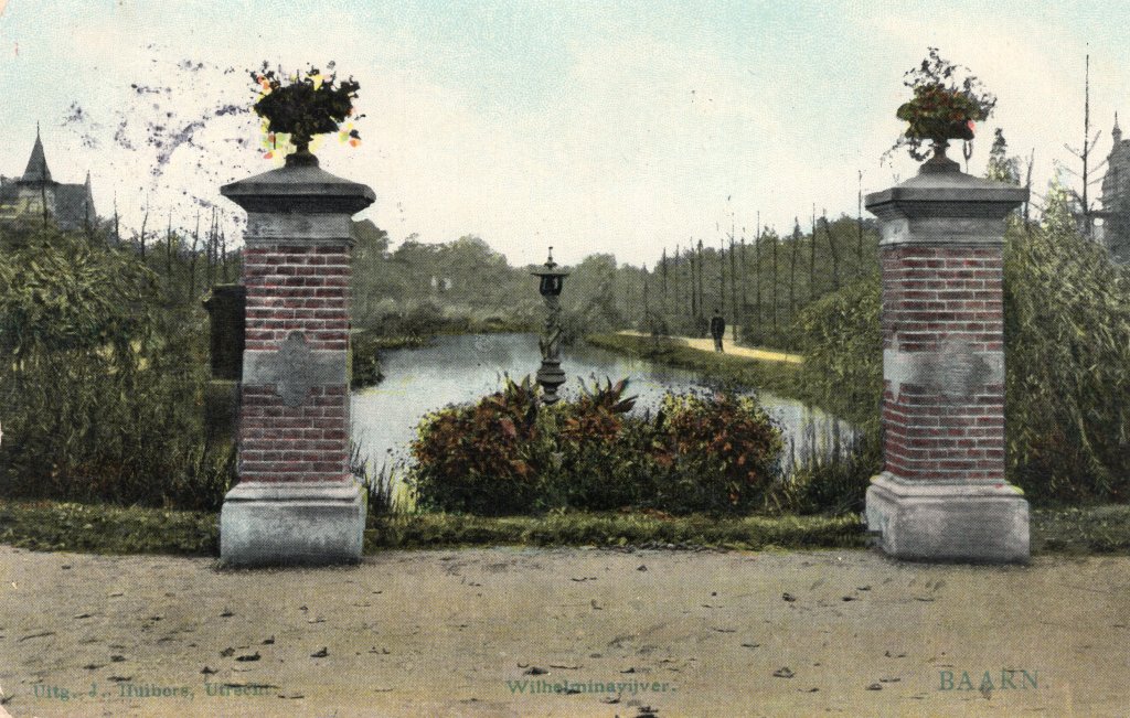 Een foto van vroeger van de Wilhelminavijver met twee pilaren met bovenop bloemstukken op de voorgrond, en daarachter de Wilhelminavijver met water