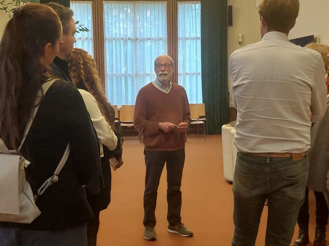 Raadslid Wim Genuit staat in de trouwzaal en geeft een rondleiding aan een groepje inwoners