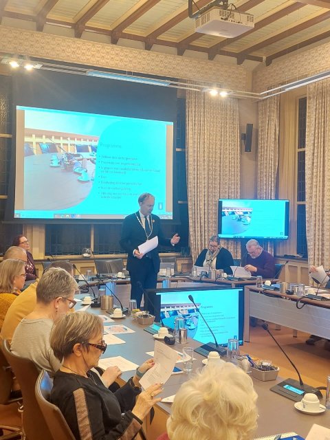 Burgemeester Mark Röell geeft spreekt tot een groep mensen die in de raadzaal rond de tafel zitten