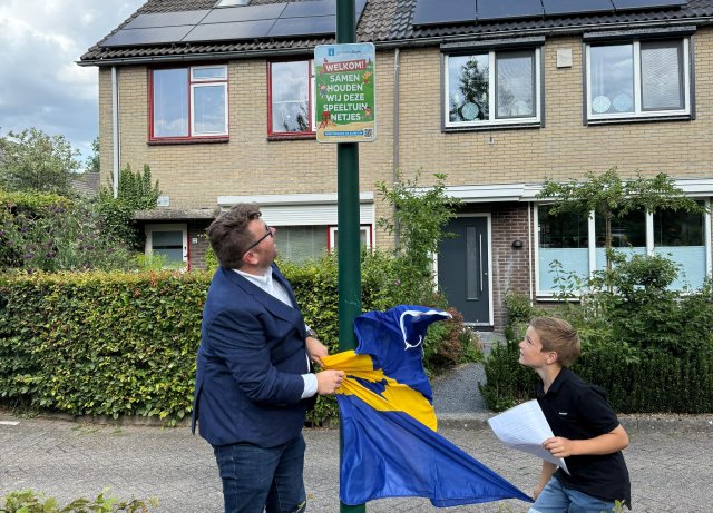 Het nieuwe speeltuinbord werd onthuld door oud-kinderburgemeester Thijs en wethouders Mark Eijbaard