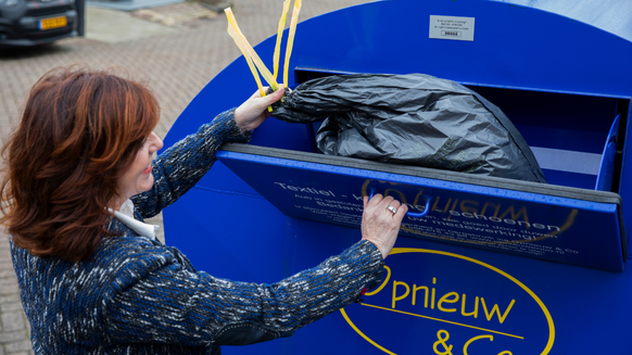 Inwoner gooit textiel in de textielcontainer