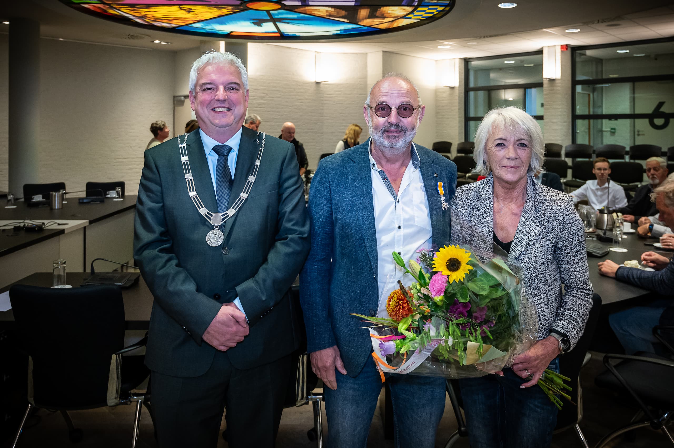 Burgemeester Eric Geurts naast Harry van de Laar met zijn partner bij toekenning Koninklijke onderscheiding