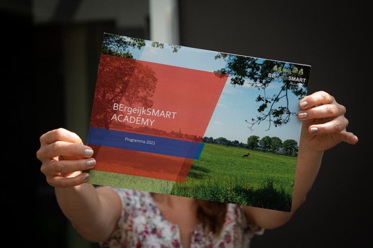 2 handen houden het programmaboekje van de BErgeijkSMART academy omhoog