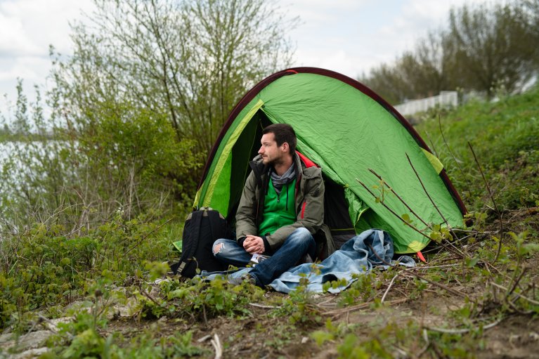 Man zit voor een tentje in het gras