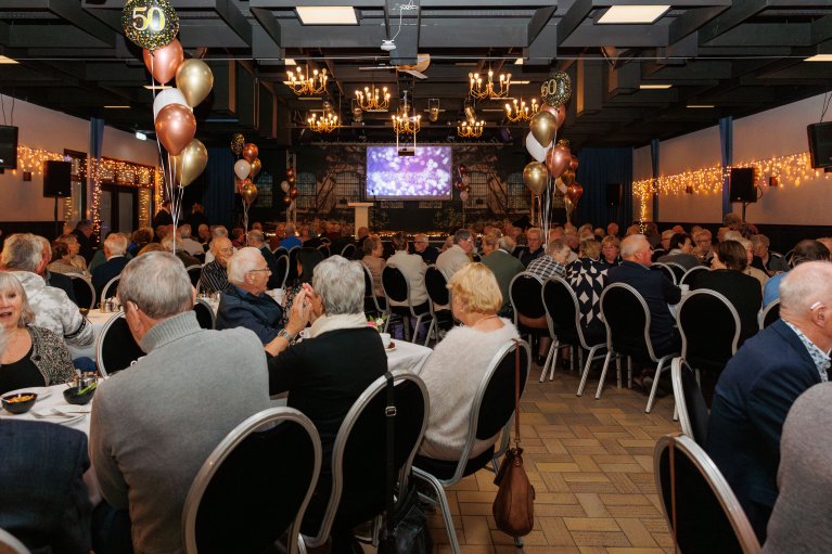 Echtparen zitten aan tafels tijdens de huldiging in een zaal van De Sleutel in Riethoven