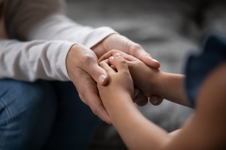 Twee mensen zitten tegenover elkaar en houden elkaars handen vast