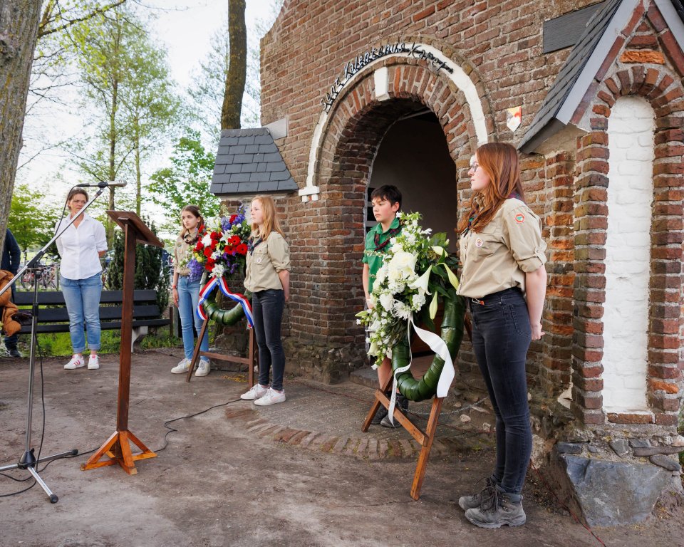 Jeugd staat voor een kapel bij de kransen voor Dodenherdenking