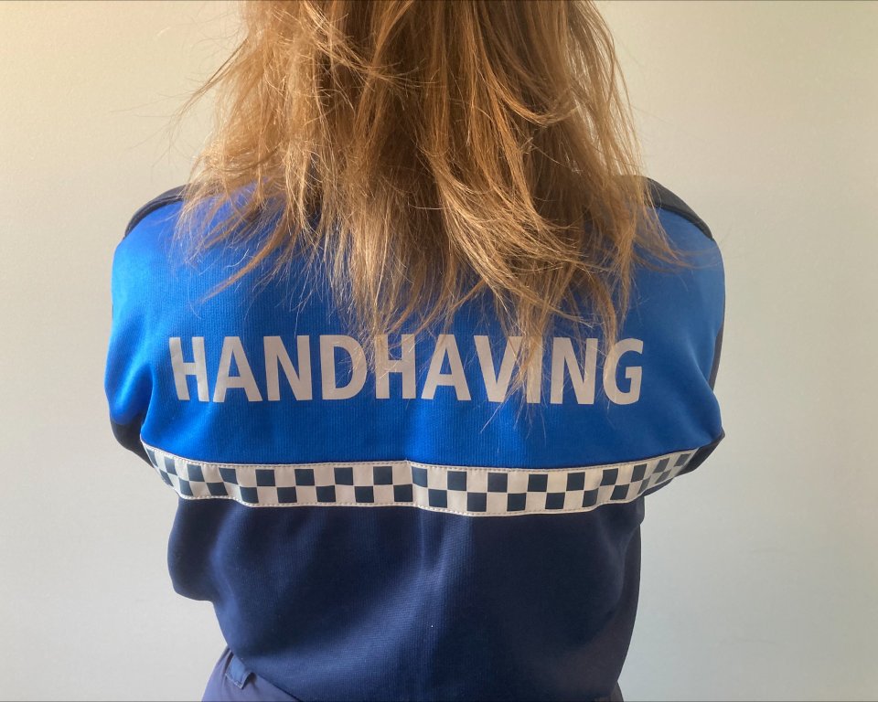 Persoon met jas aan waarop handhaving staat