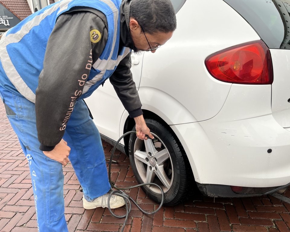 Persoon checkt bandenspanning van een auto