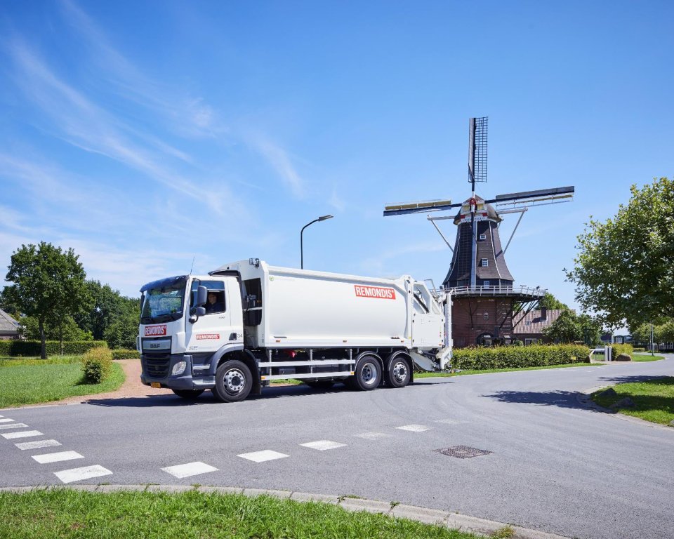 Bus van Remondis op de weg met een molen op de achtergrond