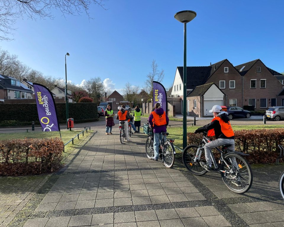 Kinderen met veiligheidshesjes op de fiets