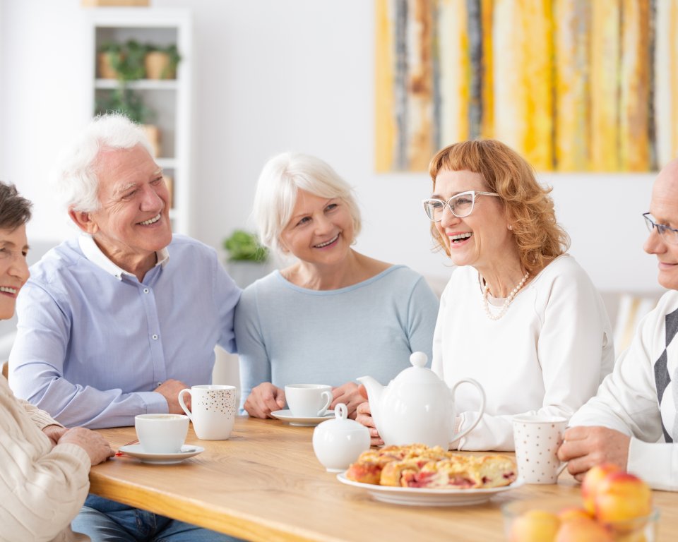Ouderen zitten thee te drinken aan tafel
