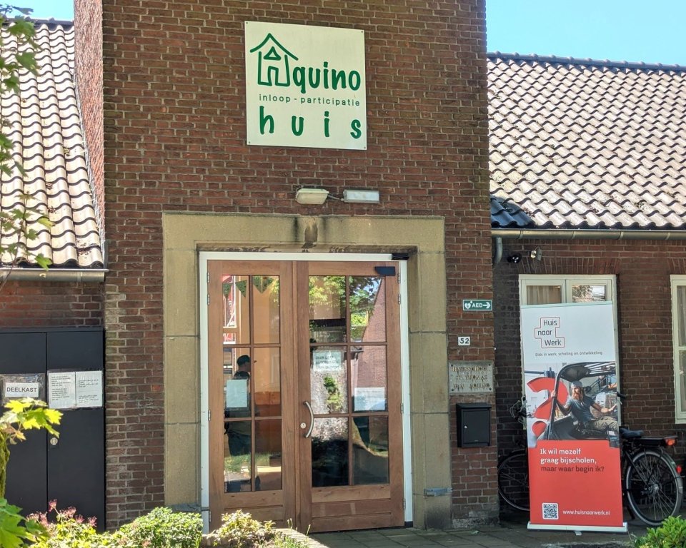 Foto van het Aquinohuis met een banner van Huis naar Werk