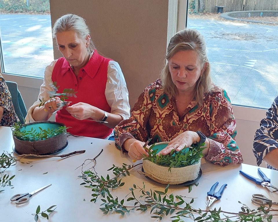 Vier dames zitten te bloemschikken