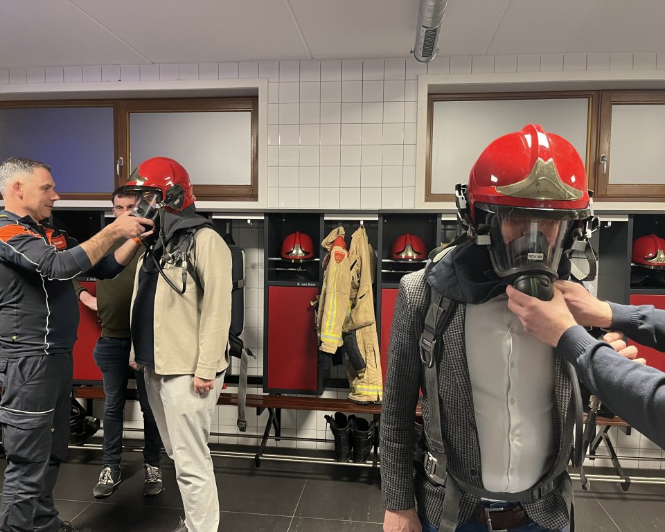 Brandweermannen krijgen hun helm met masker opgezet