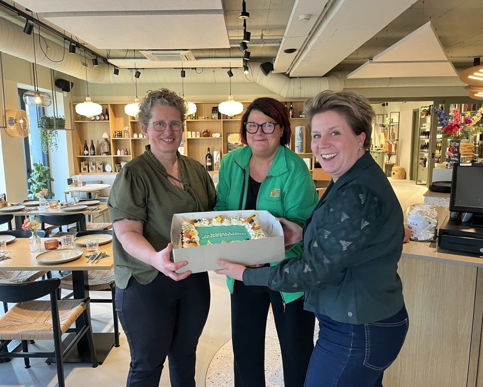 Wethouder Lindy Wijnen met twee dames bij Anders van Smaak met een taart in de handen.