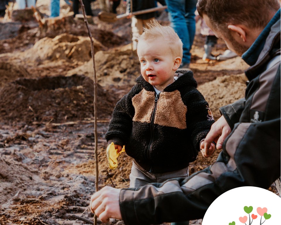 Klein kindje met vader bij een boompje in de grond planten