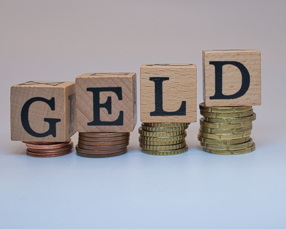 Muntgeld op stapeltjes gelegd met het woord geld erbij