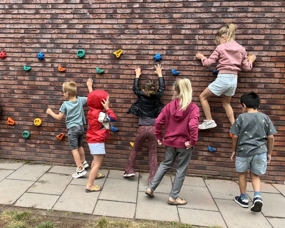 Zes kinderen klimmen op een klimmuur