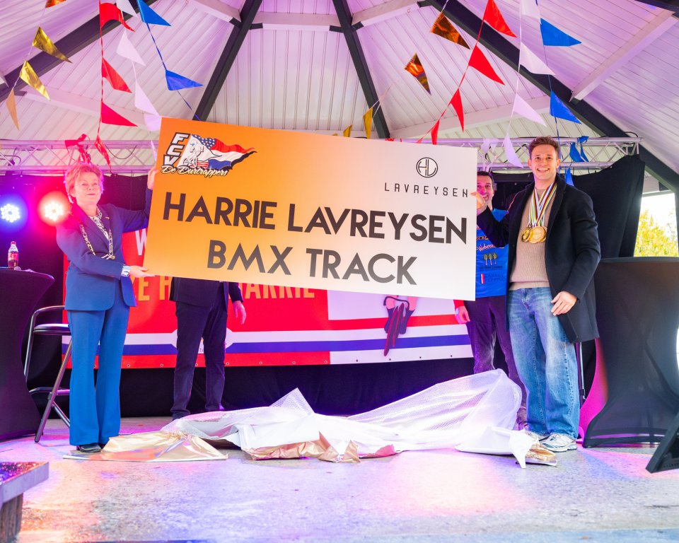 Burgemeester Wilma Delissen en Harrie Lavreysen met het bord dat de BMX baan vernoemd wordt naar Harrie