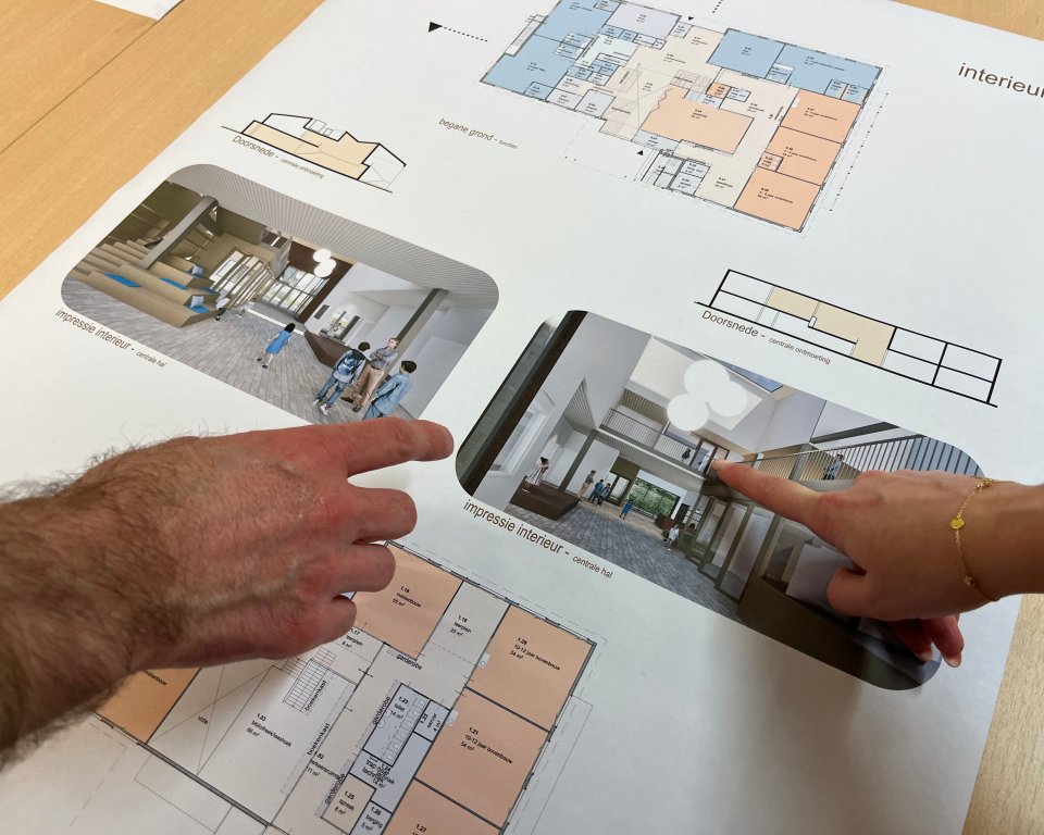 Twee handen wijzen een tekening op de bouwtekening aan