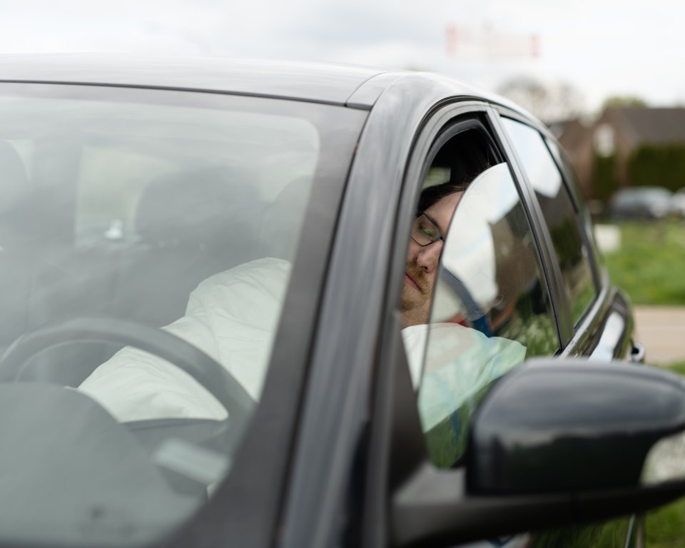 Man ligt in de auto te slapen