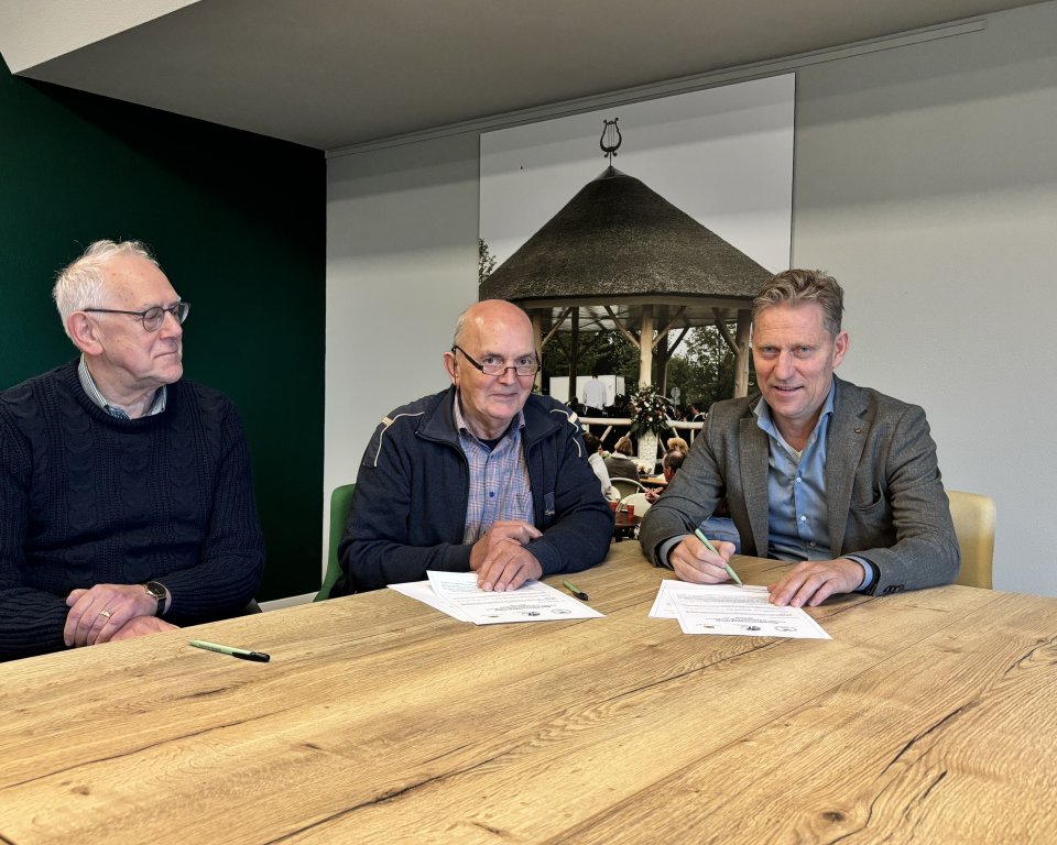 Wethouder Mathijs Kuijken ondertekent beheerovereenkomst pleintjes Riethoven aan tafel met vrijwilligers