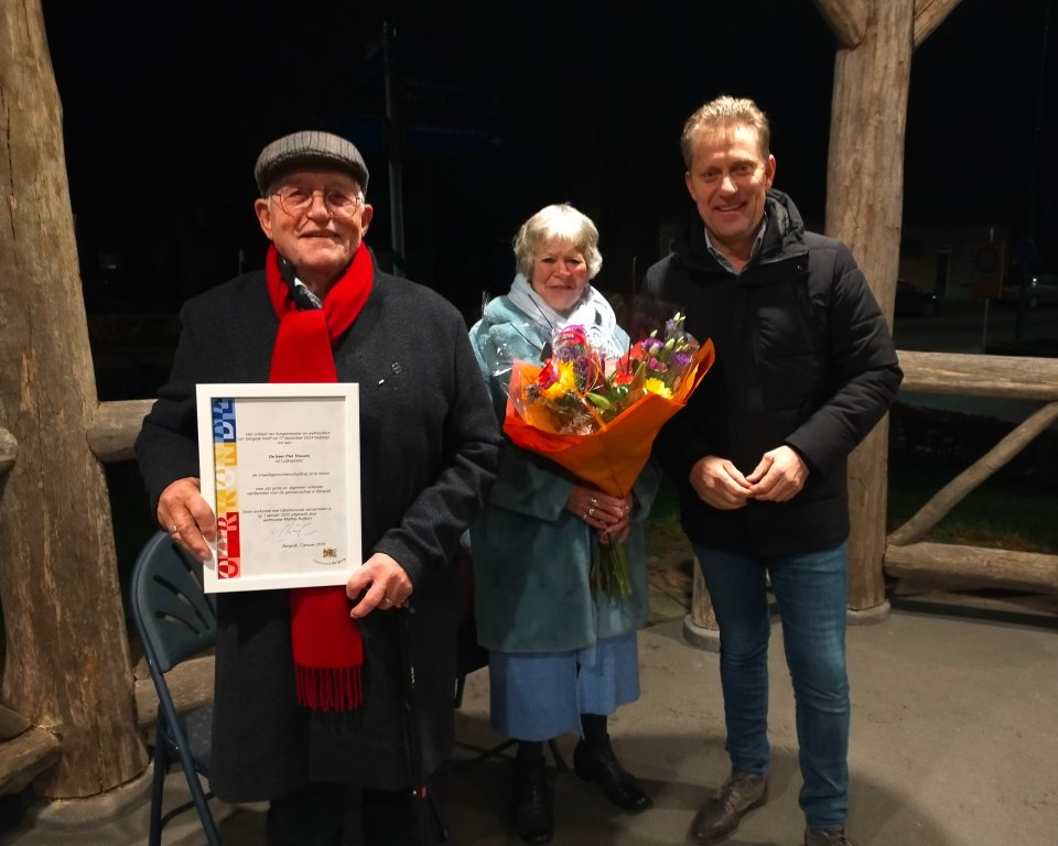 Piet Theuws, zijn vrouw en wethouder Mathijs Kuijken staan bij elkaar met de vrijwilligersonderscheiding in de handen van Piet.