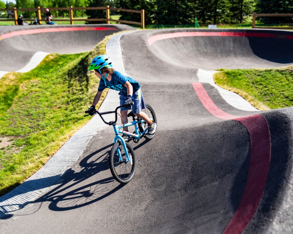 Jongen met helm op een fiets rijdend op een pumptrackbaan