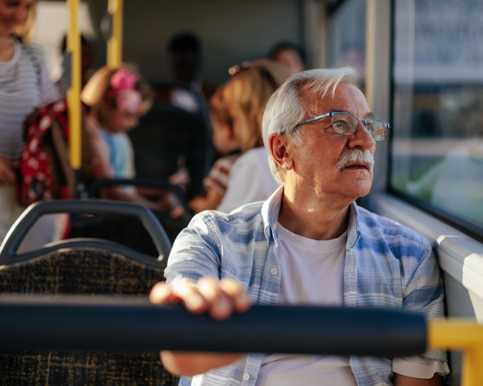 Oudere man in de bus kijkend uit het raam