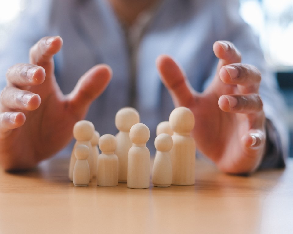 Familieopstelling in poppetjes op tafel met 2 handen eromheen