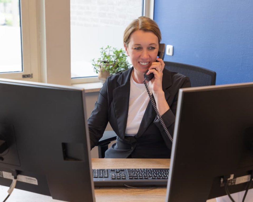 Vrouw aan de telefoon kijkend op haar computerschermen