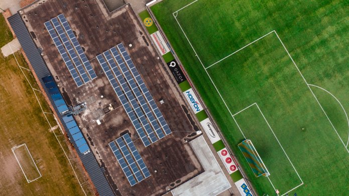 Drone foto van boven waarbij je de zonnepanelen en zonnecollectoren op het dak van RKVV Bergeijk ziet liggen